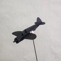 A small black cardboard airplane model of the U.S. Army P-47 Thunderbolt mounted on a thin black wire stand against a light gray textured background.