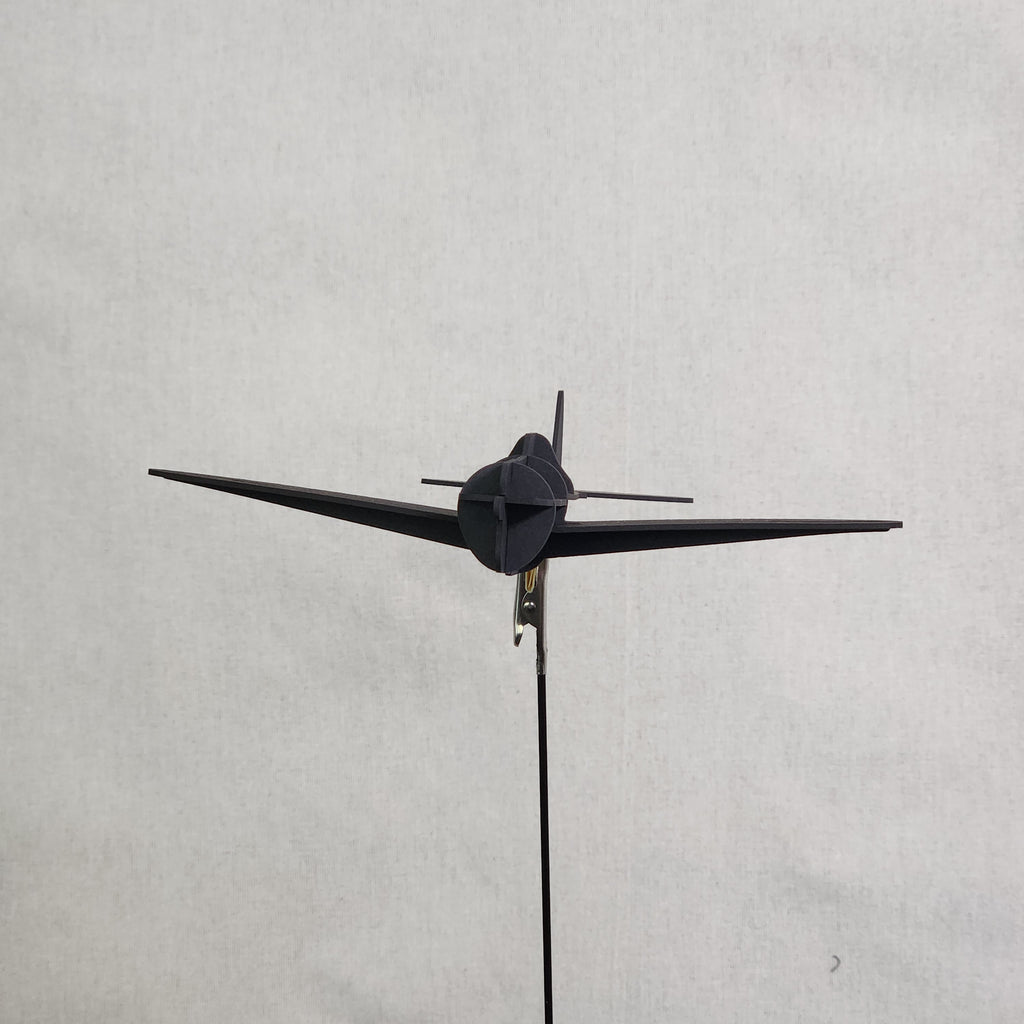 A small black cardboard airplane model of the U.S. Army P-47 Thunderbolt shown from a top-down perspective against a light gray textured background.