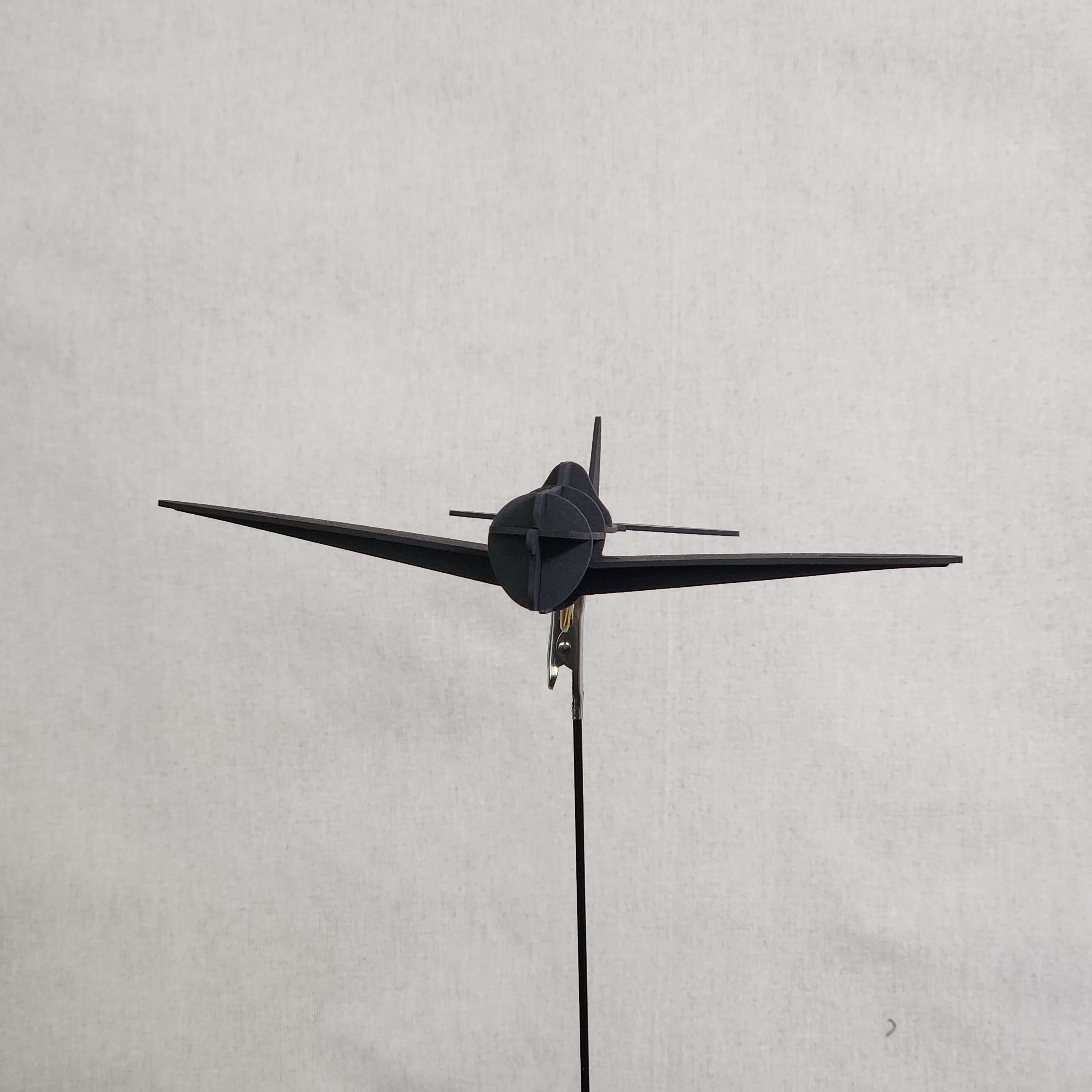 A small black cardboard airplane model of the U.S. Army P-47 Thunderbolt shown from a top-down perspective against a light gray textured background.