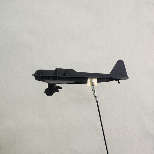 A black cardboard model airplane of the Japanese D3A1 Val, shown against a light gray textured background.